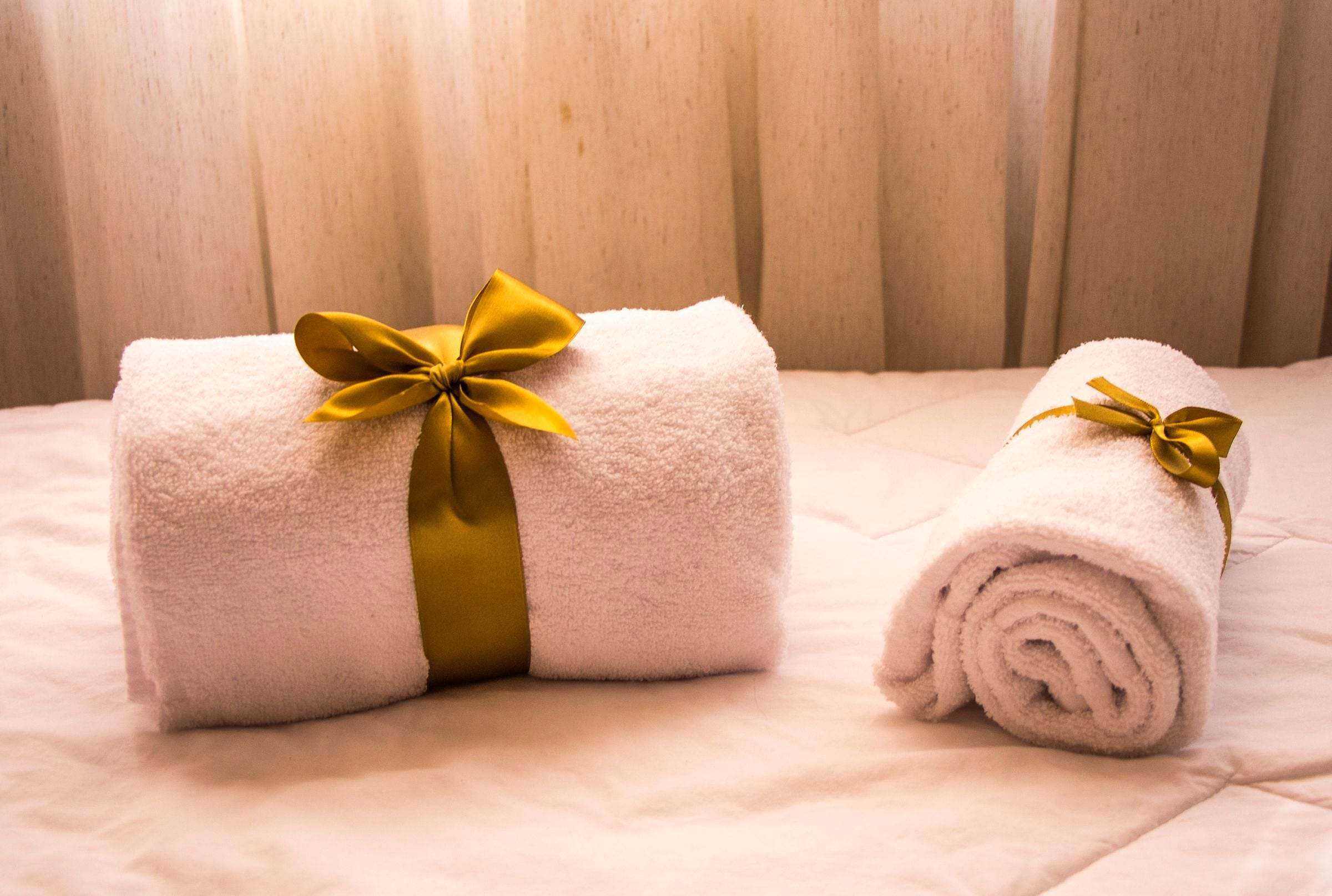Toallas enrolladas con lazo dorado, como un regalo de spa