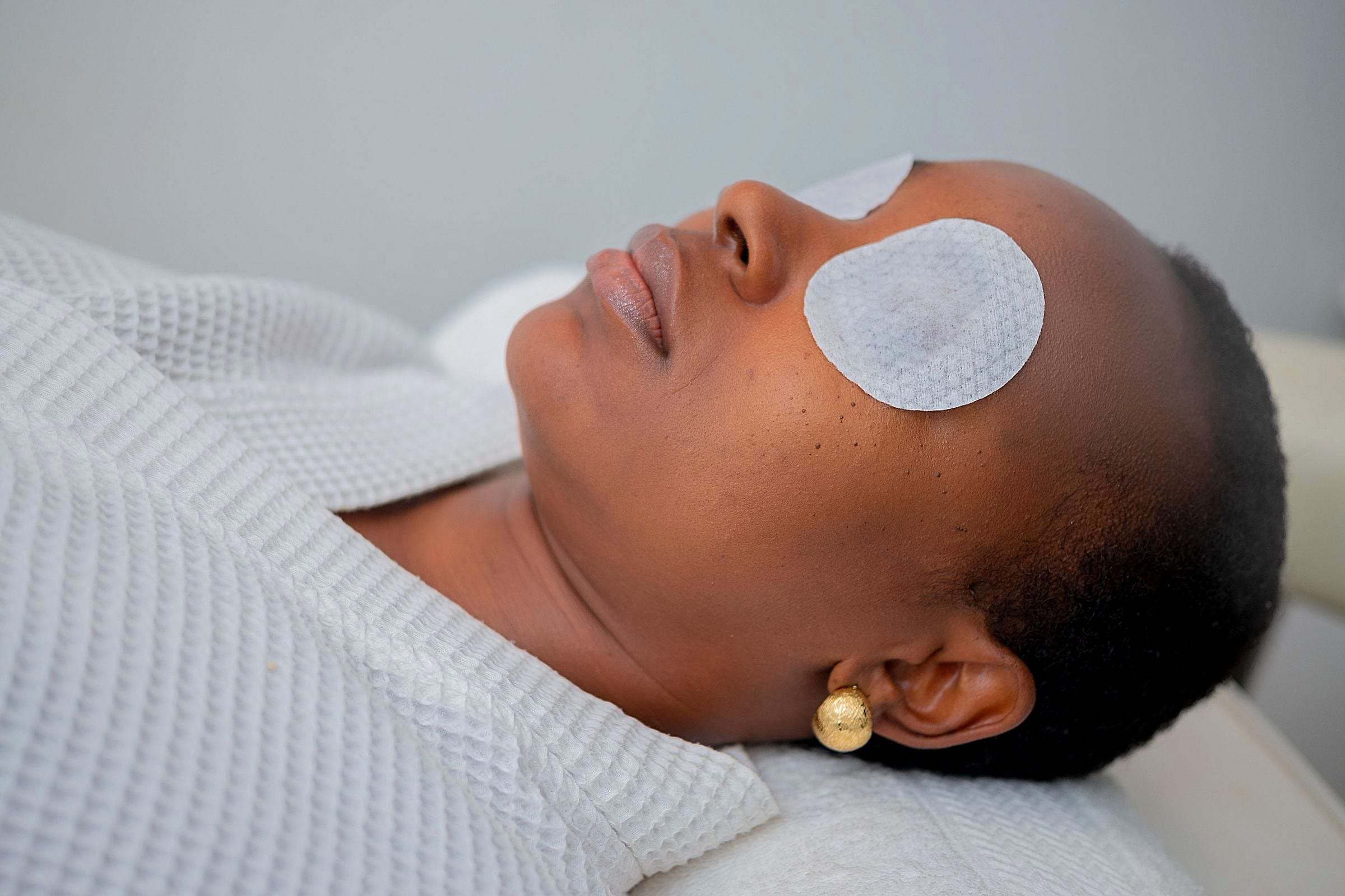 Mujer relajada con parches de algodón en los ojos durante un tratamiento facial