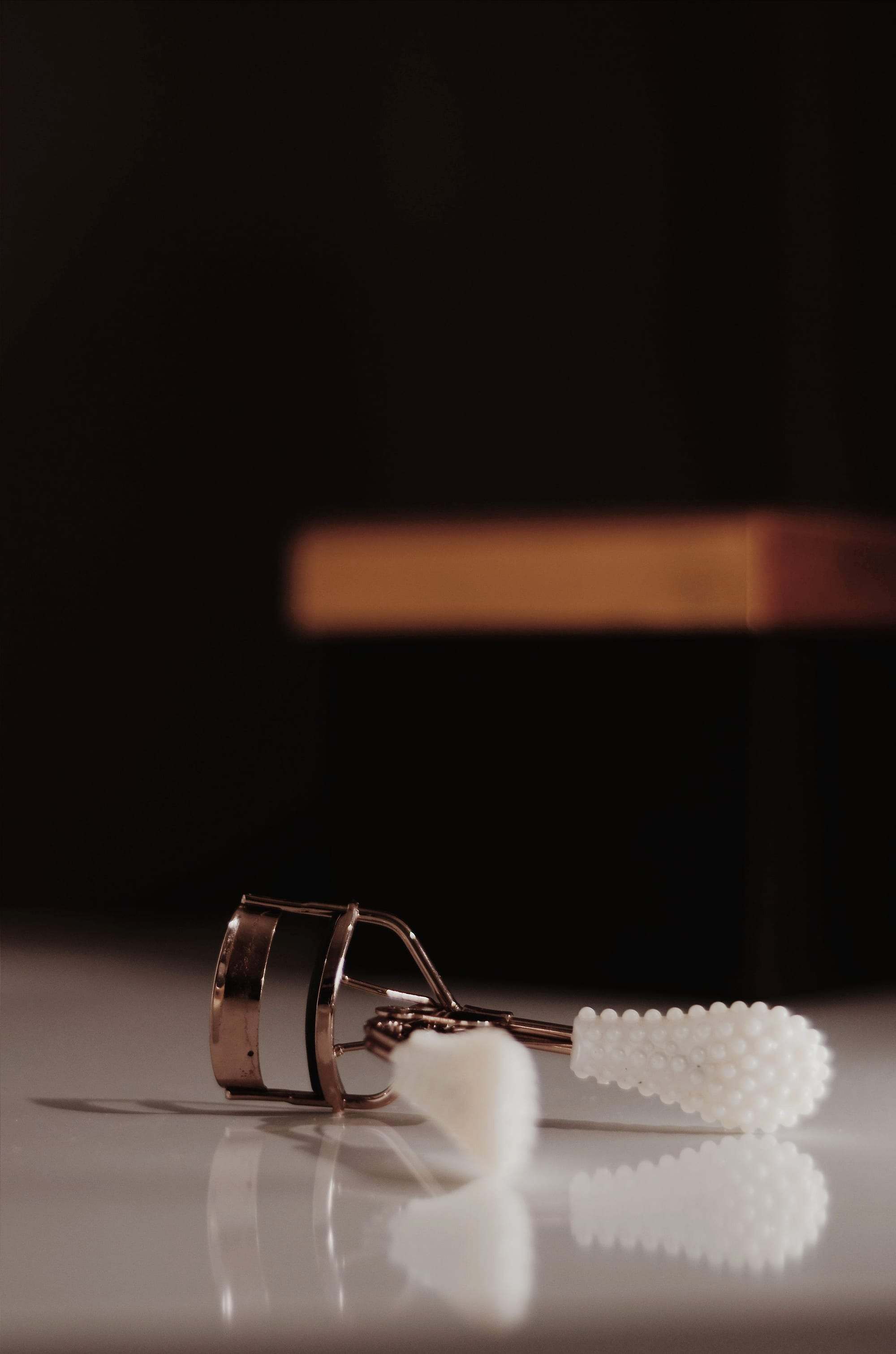 Rizador de pestañas sobre una superficie brillante con fondo oscuro