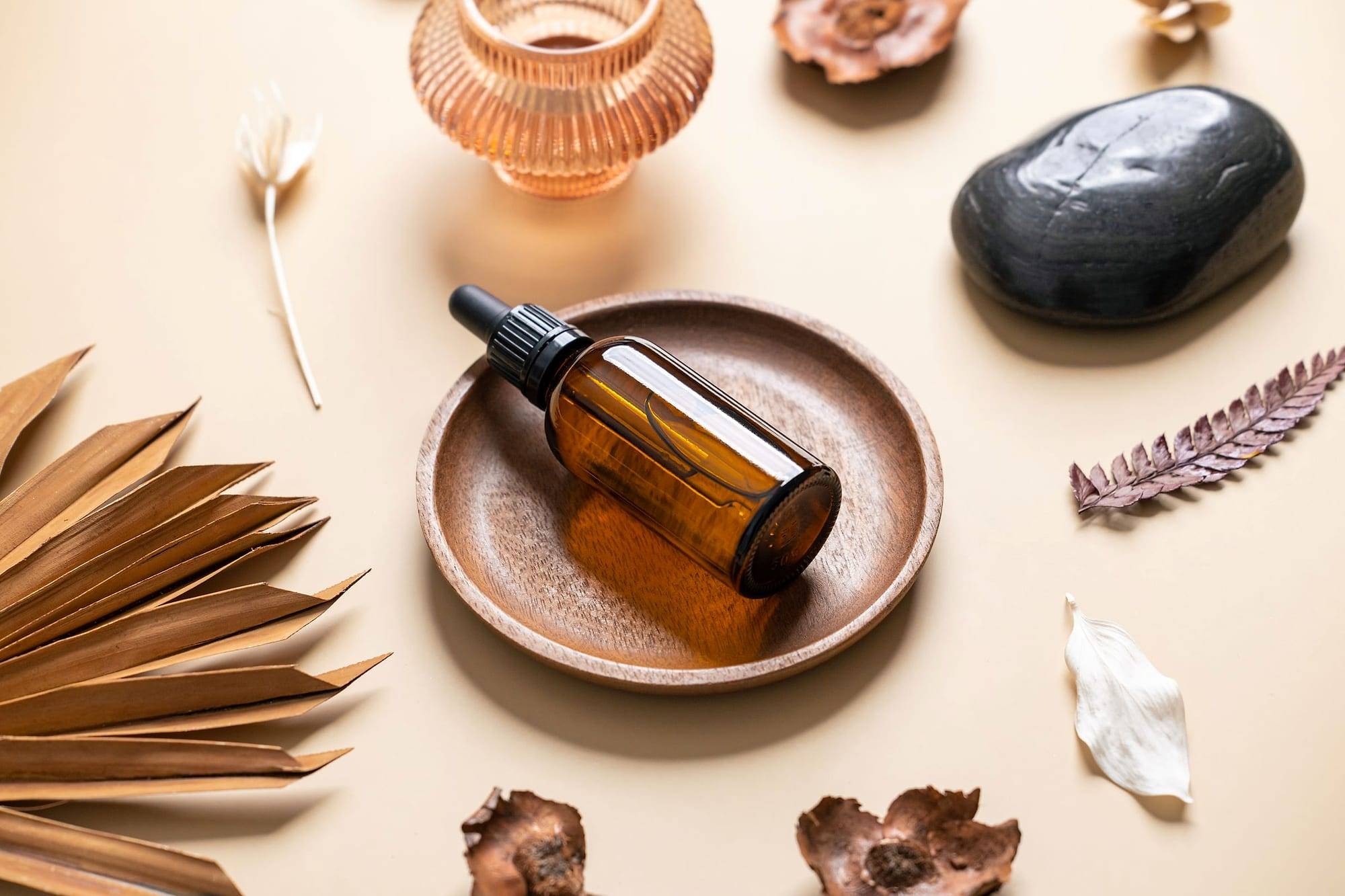 Massage oil bottle on a wooden dish with stones and dried leaves