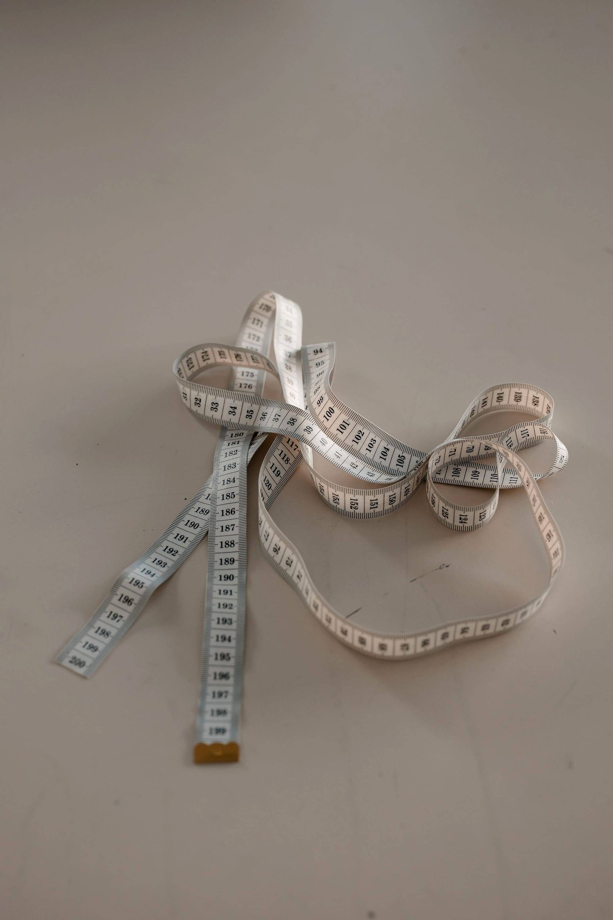 White measuring tape curled on a neutral background