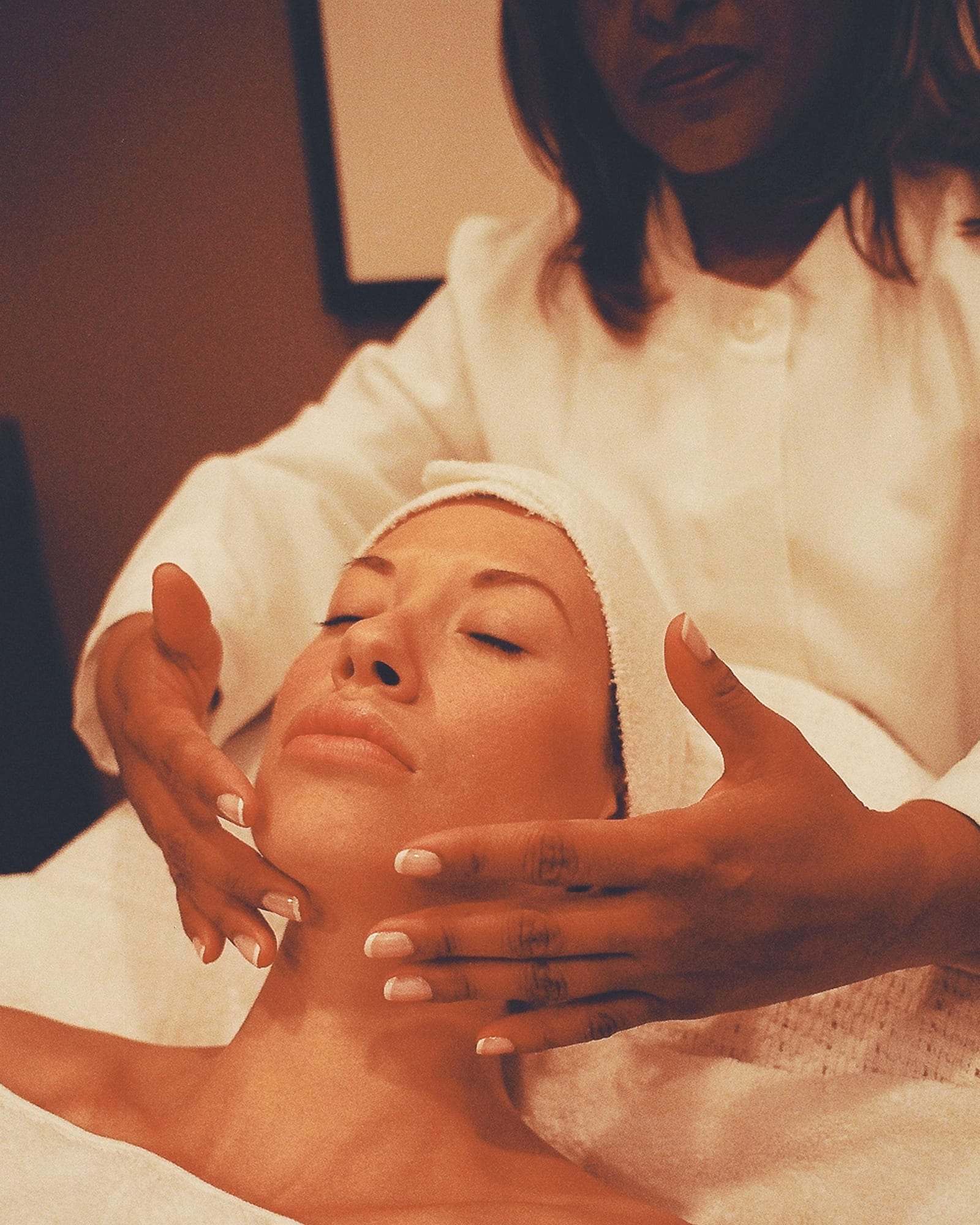 Masaje facial manual con las manos de la terapeuta sobre el rostro y el cuello