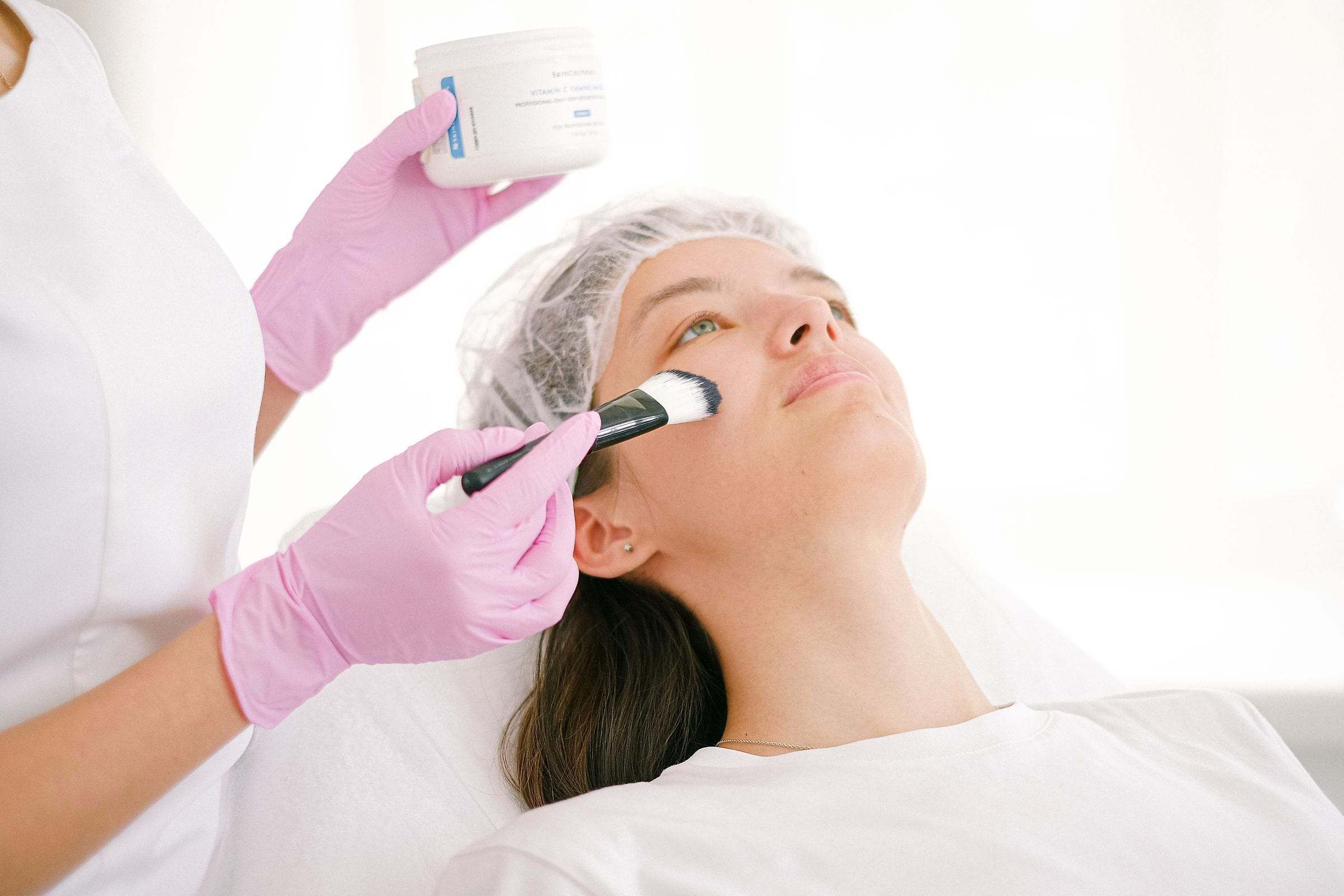 Aplicación de un peeling con pincel sobre el rostro de una clienta