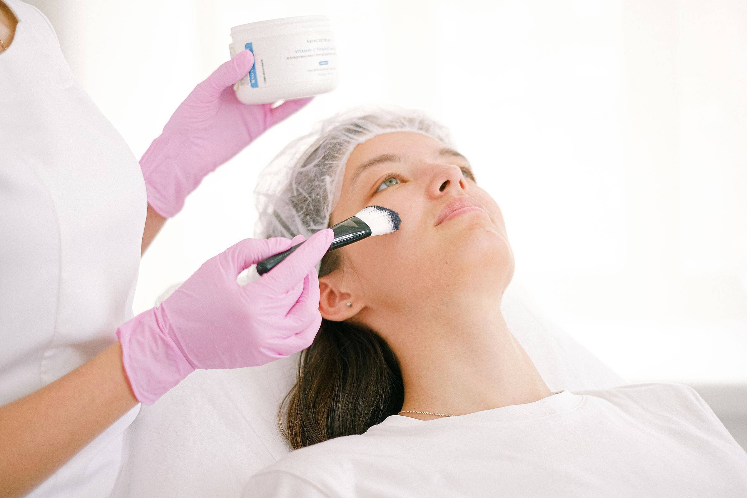 Aplicación de un peeling con pincel sobre el rostro de una clienta