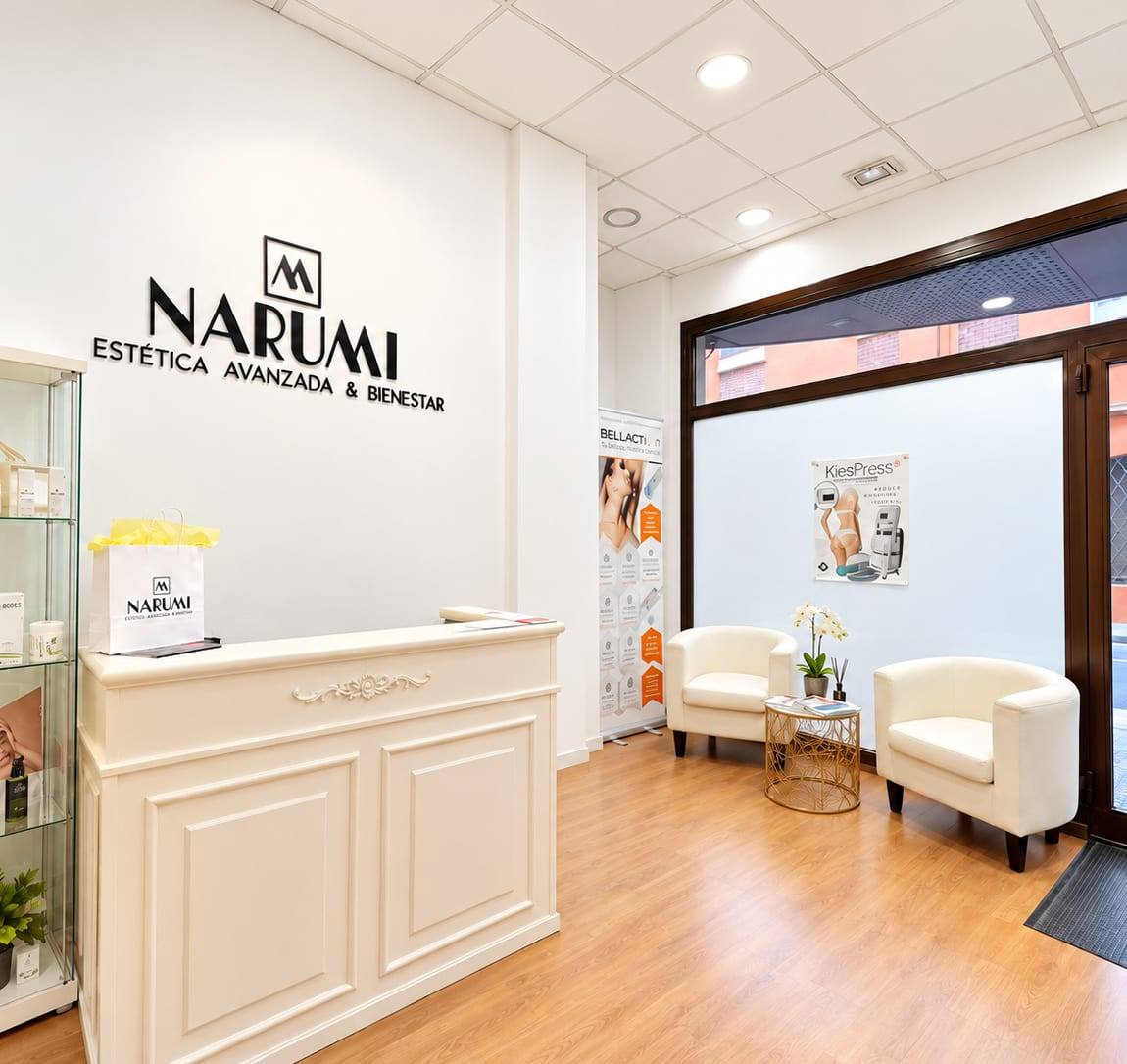Recepción de Narumi Estética Avanzada & Bienestar en Málaga, con el logotipo en la pared, el mostrador blanco y la zona de espera